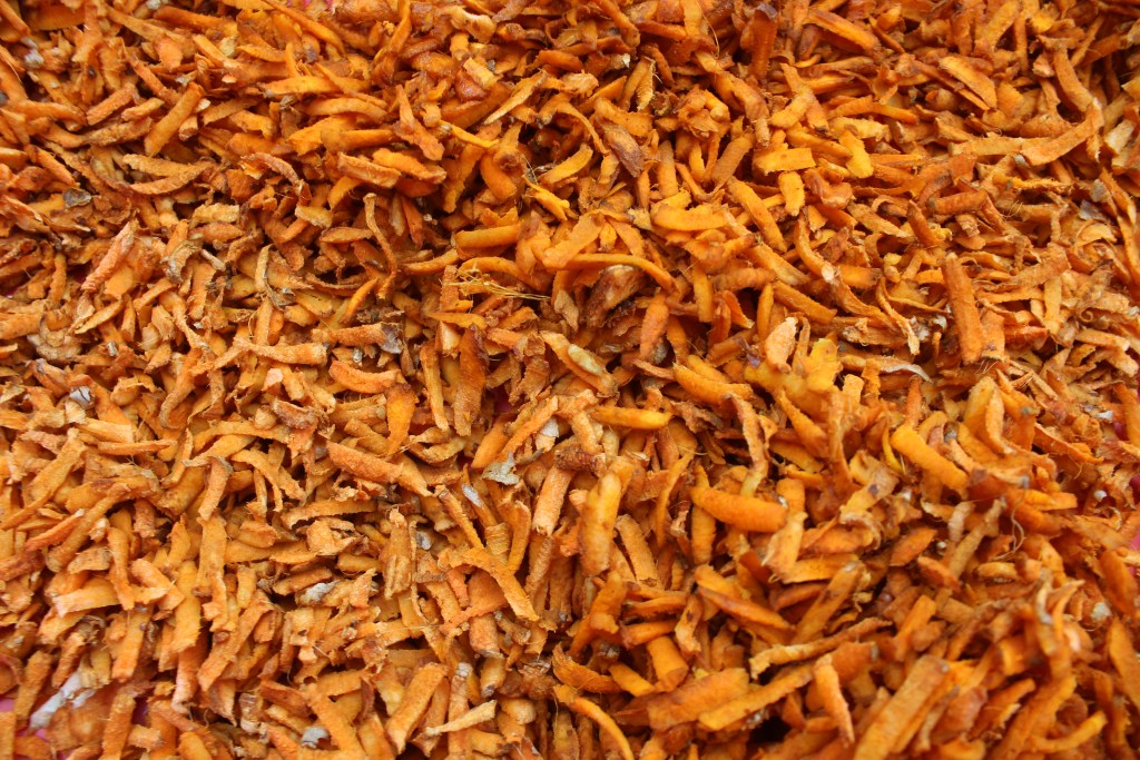 A close-up view of dried, shredded orange carrot peels, showcasing their textured surface and vibrant color.